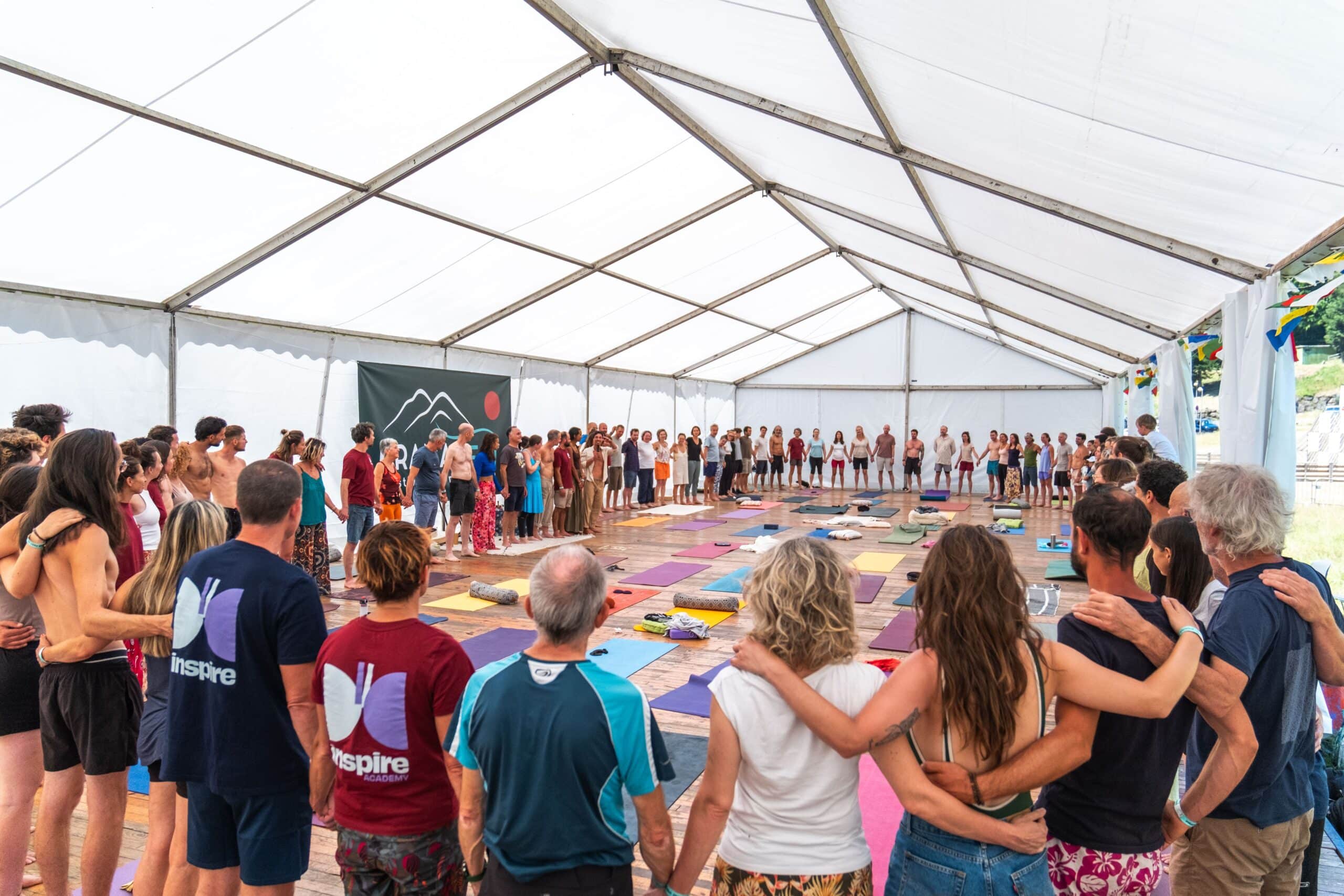 Cercle de partage Inspire Academy, tapis de yoga au sol sous chapiteau. Esprit de communauté.
