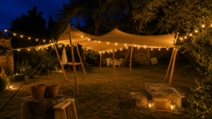 Tente stretch illuminée de guirlandes dans un jardin de nuit avec lanternes et mobilier de réception.