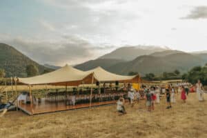 Mariage champêtre sous tente stretch avec invités face aux montagnes.