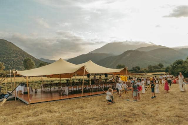 Mariage champêtre sous tente stretch avec invités face aux montagnes.